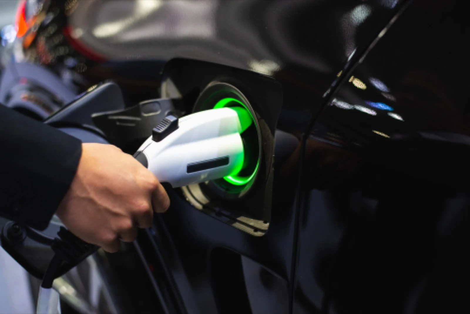 Hand plugging a charging connector into an electric car